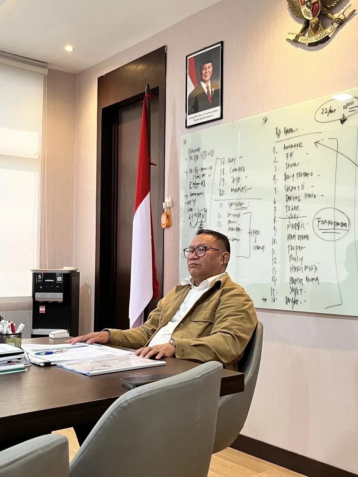 Pejabat BP Batam di meja kerja, papan tulis dan bendera merah putih di belakangnya